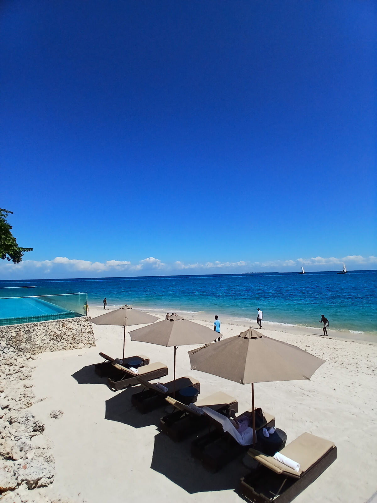 White sandy beach with sun loungers and turquoise sea near Stone Town, Zanzibar